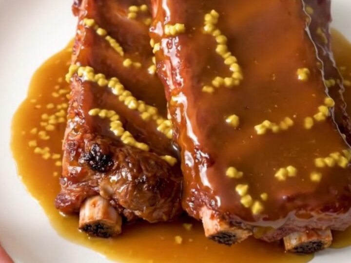 A plate of glossy, golden-brown honey mustard country-style ribs served on a clean white plate.