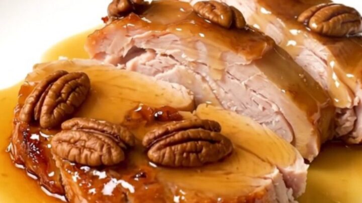 A close-up of sliced maple pecan turkey tenderloin medallions with a glossy glaze on a white plate.