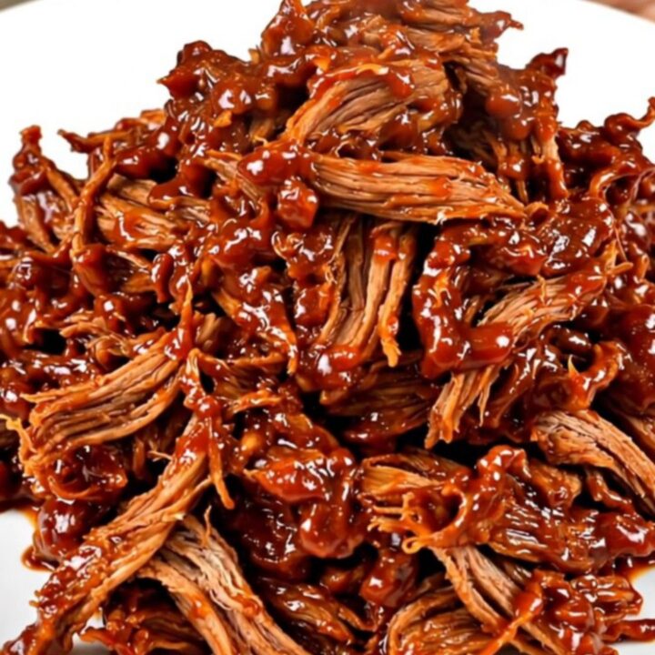 A white plate topped with a generous portion of glossy, shredded Korean-style pork with visible steam rising from it.