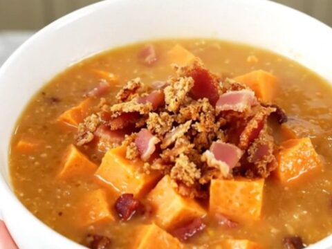 A steaming bowl of creamy sweet potato and bacon chowder garnished with crispy bacon bits.