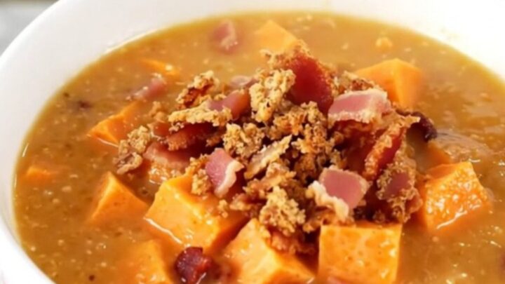 A steaming bowl of creamy sweet potato and bacon chowder garnished with crispy bacon bits.