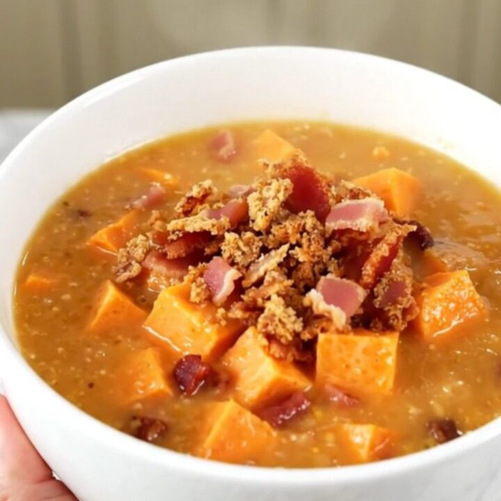 A steaming bowl of creamy sweet potato and bacon chowder garnished with crispy bacon bits.