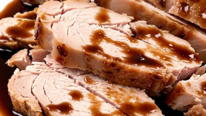 Succulent, sliced balsamic glazed turkey tenderloin on a clean white plate with a glossy dark reduction.
