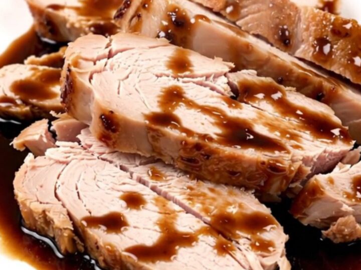 Succulent, sliced balsamic glazed turkey tenderloin on a clean white plate with a glossy dark reduction.