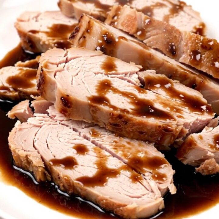 Succulent, sliced balsamic glazed turkey tenderloin on a clean white plate with a glossy dark reduction.