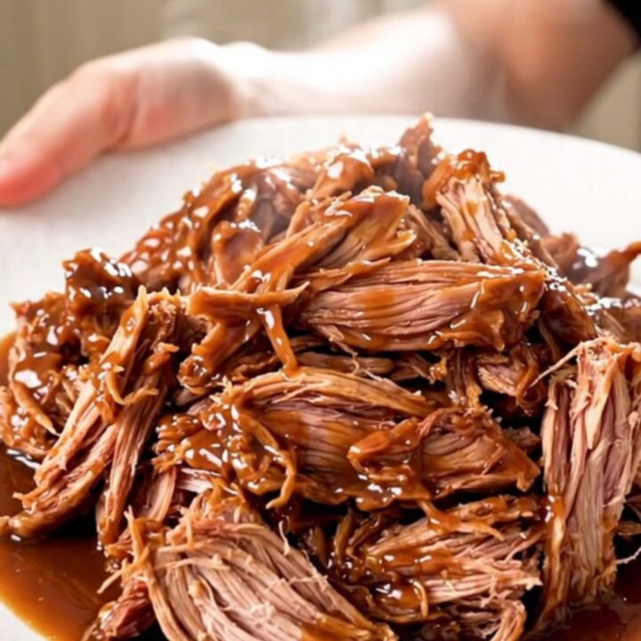 A close-up view of juicy, shredded chipotle lime pulled pork served on a white plate.