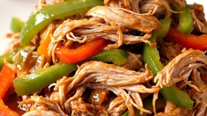 A white plate filled with shredded fajita turkey tenderloin and colorful peppers.
