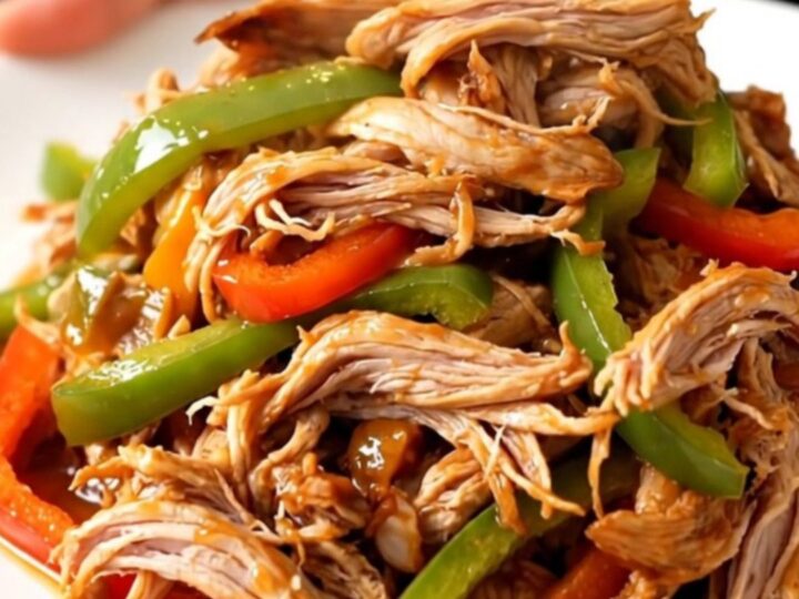 A white plate filled with shredded fajita turkey tenderloin and colorful peppers.