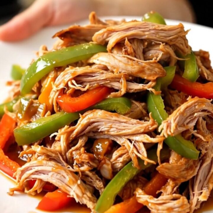 A white plate filled with shredded fajita turkey tenderloin and colorful peppers.
