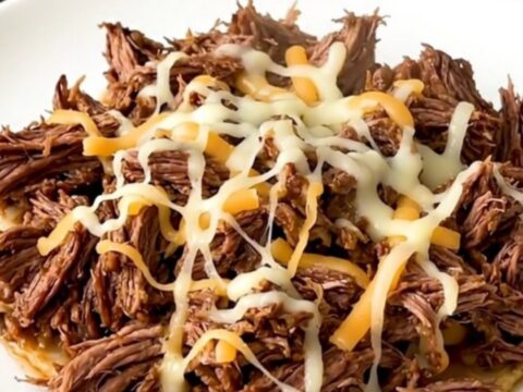 A slow cooker filled with tender, shredded beef mixed with green chiles and melted pepper jack cheese.
