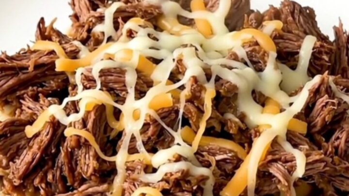 A slow cooker filled with tender, shredded beef mixed with green chiles and melted pepper jack cheese.