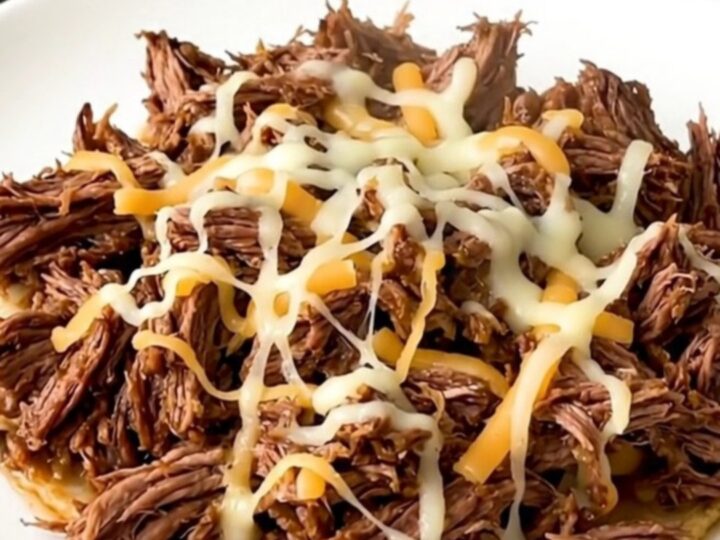 A slow cooker filled with tender, shredded beef mixed with green chiles and melted pepper jack cheese.
