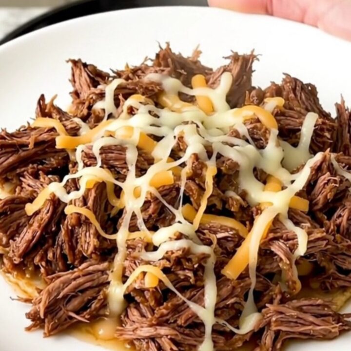 A slow cooker filled with tender, shredded beef mixed with green chiles and melted pepper jack cheese.
