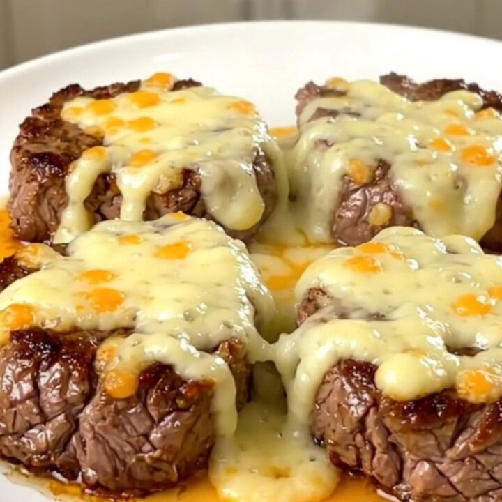 A plate of tender, slow-cooked steak bites coated in melted pepper jack cheese and green chiles.