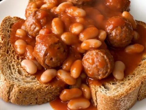 A rustic crockpot filled with steaming Italian sausage, white beans, and crushed tomatoes.
