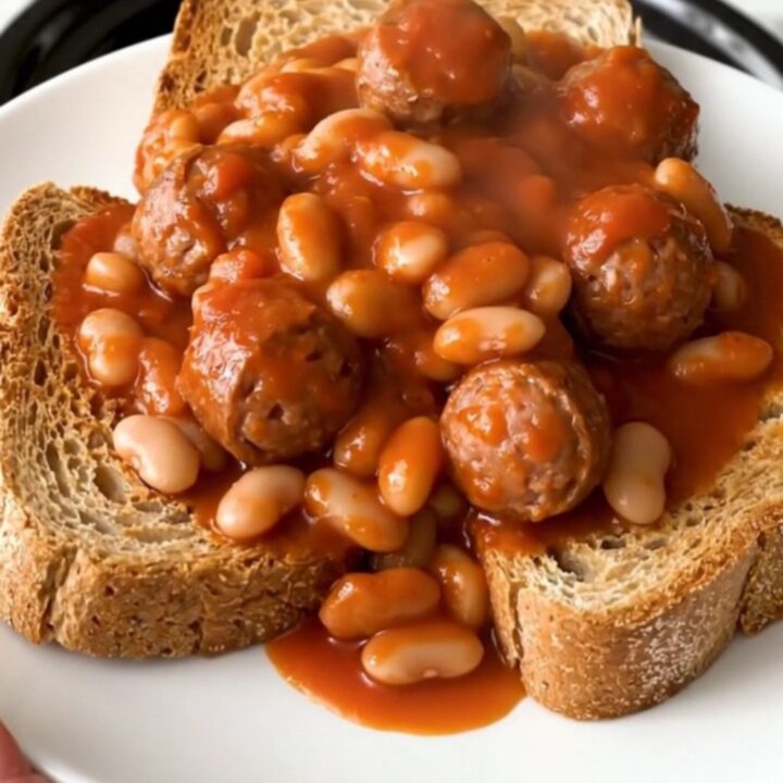 A rustic crockpot filled with steaming Italian sausage, white beans, and crushed tomatoes.