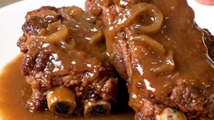 Slow-cooked country-style pork ribs covered in a rich, savory onion and mushroom gravy on a white plate.