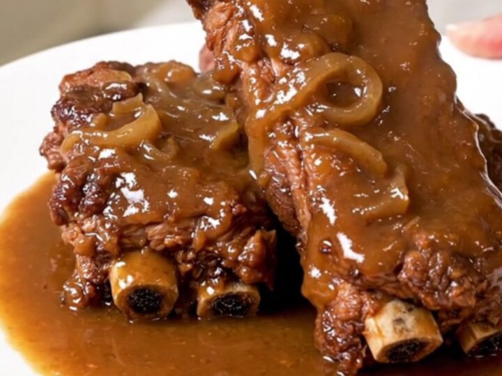 Slow-cooked country-style pork ribs covered in a rich, savory onion and mushroom gravy on a white plate.