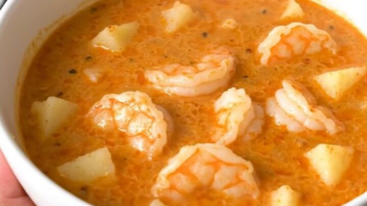 A top-down view of a black slow cooker filled with a creamy Cajun shrimp and potato chowder.