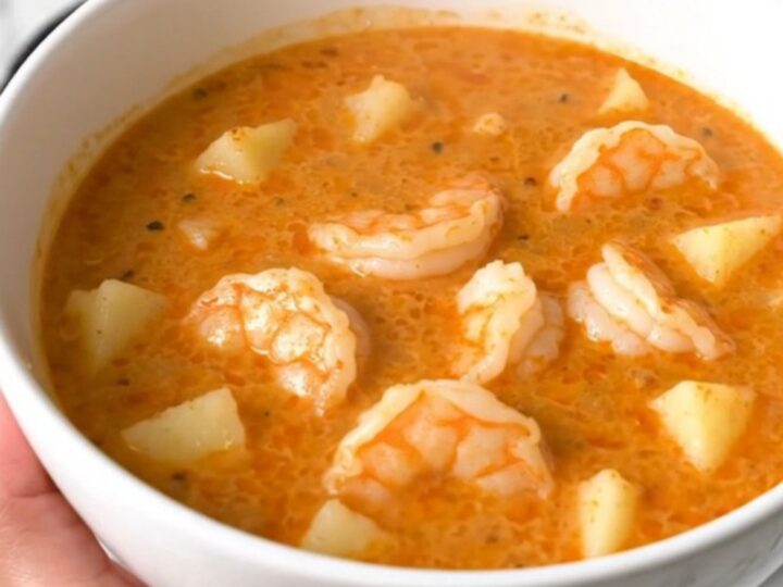 A top-down view of a black slow cooker filled with a creamy Cajun shrimp and potato chowder.