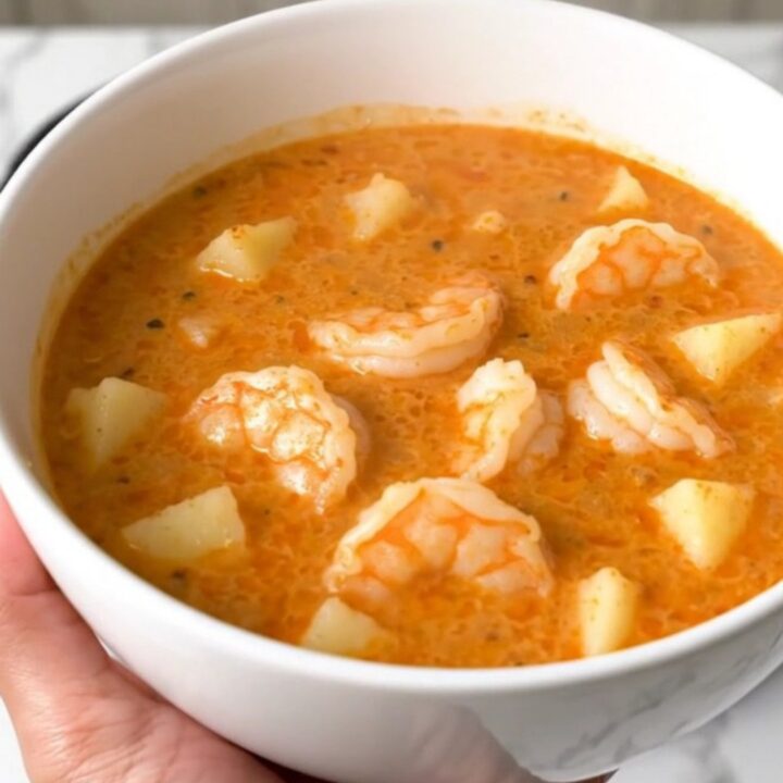 A top-down view of a black slow cooker filled with a creamy Cajun shrimp and potato chowder.
