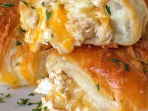 A close-up of flaky golden crescent rolls pulled apart to reveal steaming chicken and melted cheese
