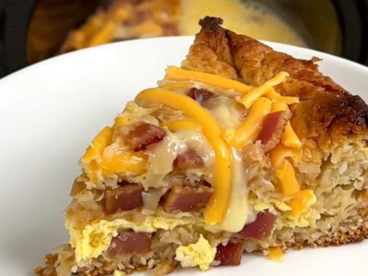 A warm, steaming slice of bacon and cheddar breakfast casserole on a white plate.
