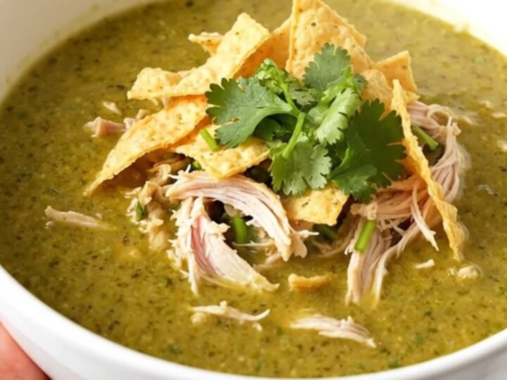 A steaming bowl of creamy green enchilada chicken soup topped with cilantro and tortilla strips.
