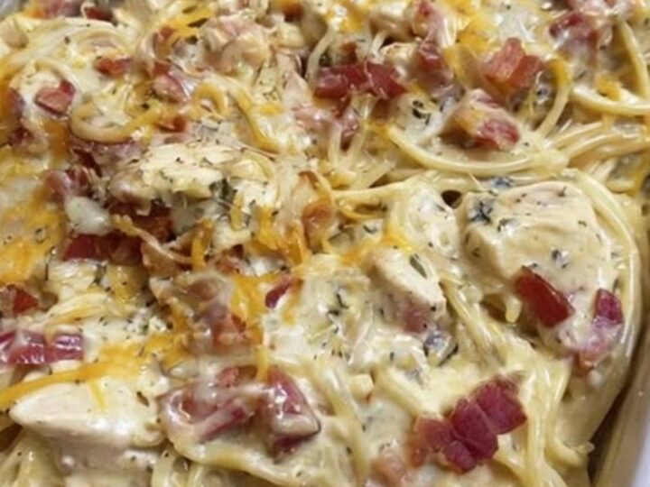 A golden-brown chicken spaghetti bake in a baking dish, topped with melted cheddar cheese and crispy bacon bits
