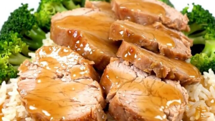 A slow cooker filled with raw pork tenderloin, green onions, and honey soy sauce.