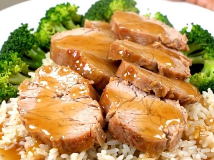 A slow cooker filled with raw pork tenderloin, green onions, and honey soy sauce.