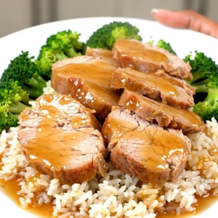 A slow cooker filled with raw pork tenderloin, green onions, and honey soy sauce.