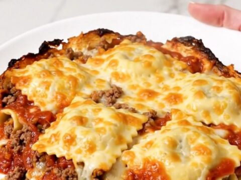 A top-down view of the cheesy beef ravioli casserole inside a black slow cooker insert.