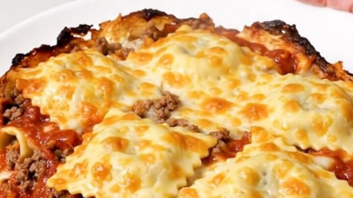 A top-down view of the cheesy beef ravioli casserole inside a black slow cooker insert.