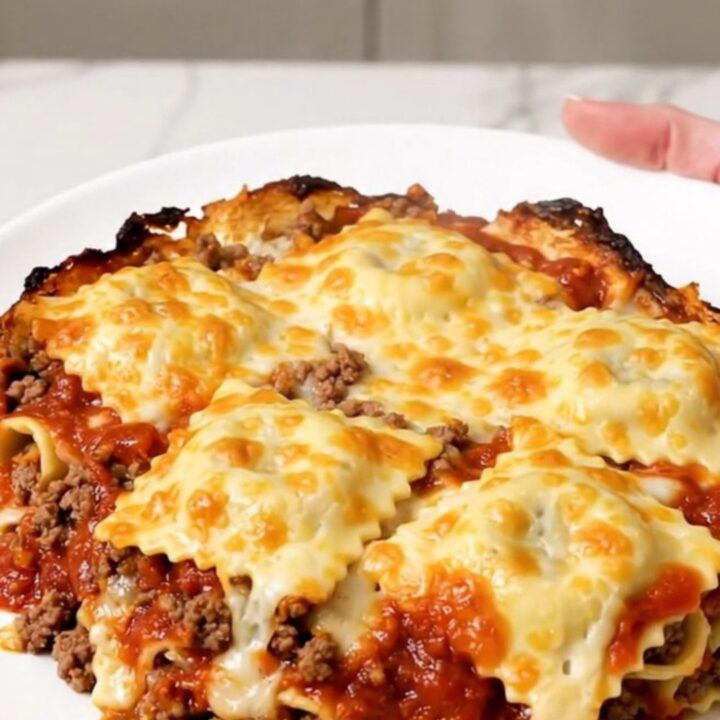 A top-down view of the cheesy beef ravioli casserole inside a black slow cooker insert.