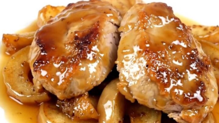 A close-up of sliced turkey medallions topped with spiced apples on a white plate.