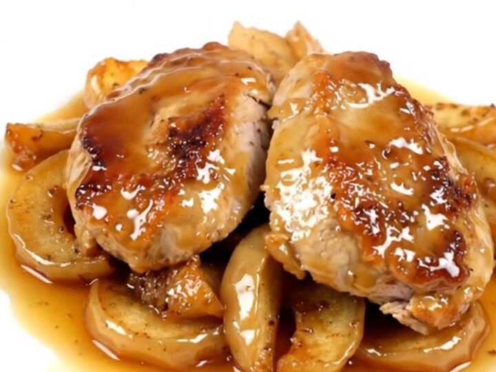 A close-up of sliced turkey medallions topped with spiced apples on a white plate.