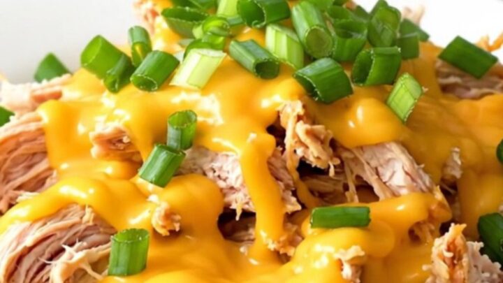 Slow cooker chicken breasts topped with creamy cheddar sauce and fresh green onions.