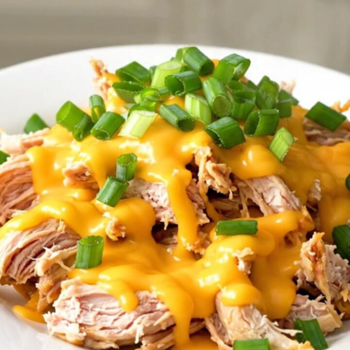 Slow cooker chicken breasts topped with creamy cheddar sauce and fresh green onions.