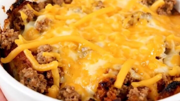 A steaming, savory slow cooker beef tamale casserole served in a white bowl with melted cheese.