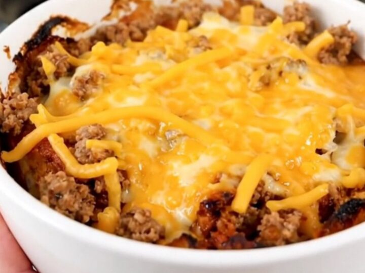 A steaming, savory slow cooker beef tamale casserole served in a white bowl with melted cheese.