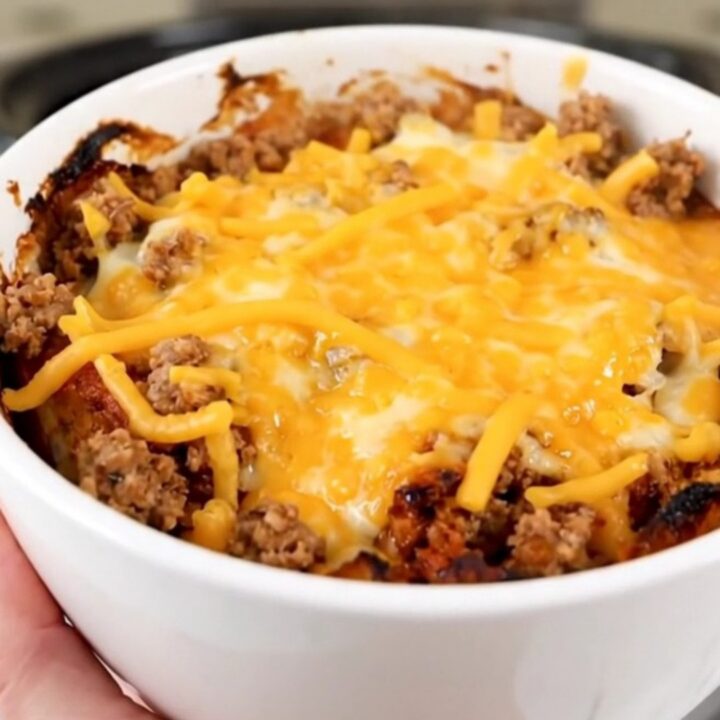 A steaming, savory slow cooker beef tamale casserole served in a white bowl with melted cheese.