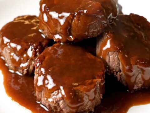 A close-up of glossy, bourbon-glazed steak bites in a slow cooker, looking tender and flavorful.