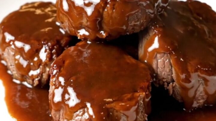 A close-up of glossy, bourbon-glazed steak bites in a slow cooker, looking tender and flavorful.