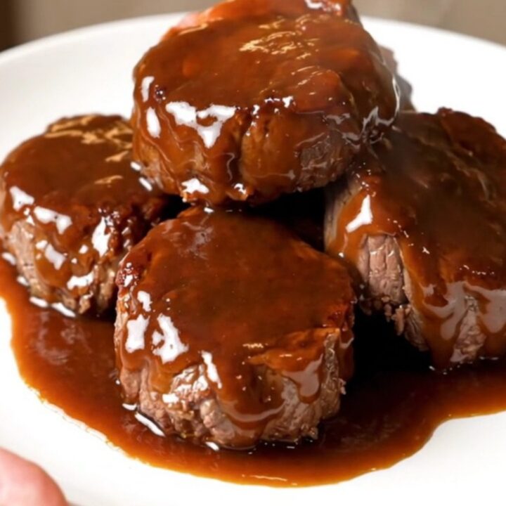 A close-up of glossy, bourbon-glazed steak bites in a slow cooker, looking tender and flavorful.