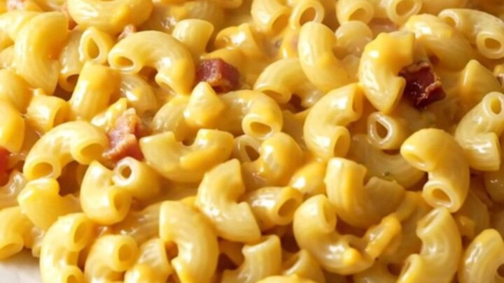 A slow cooker filled with creamy macaroni and cheese featuring visible bacon bits and a hint of smoked paprika.