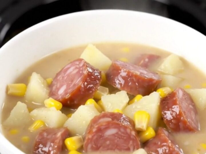 A rustic black slow cooker filled with a creamy smoked sausage and potato chowder, ready to be served.