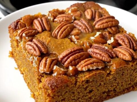 A warm pumpkin praline dump cake in a slow cooker with a golden crunchy pecan topping.