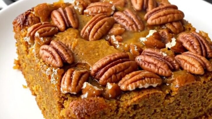 A warm pumpkin praline dump cake in a slow cooker with a golden crunchy pecan topping.