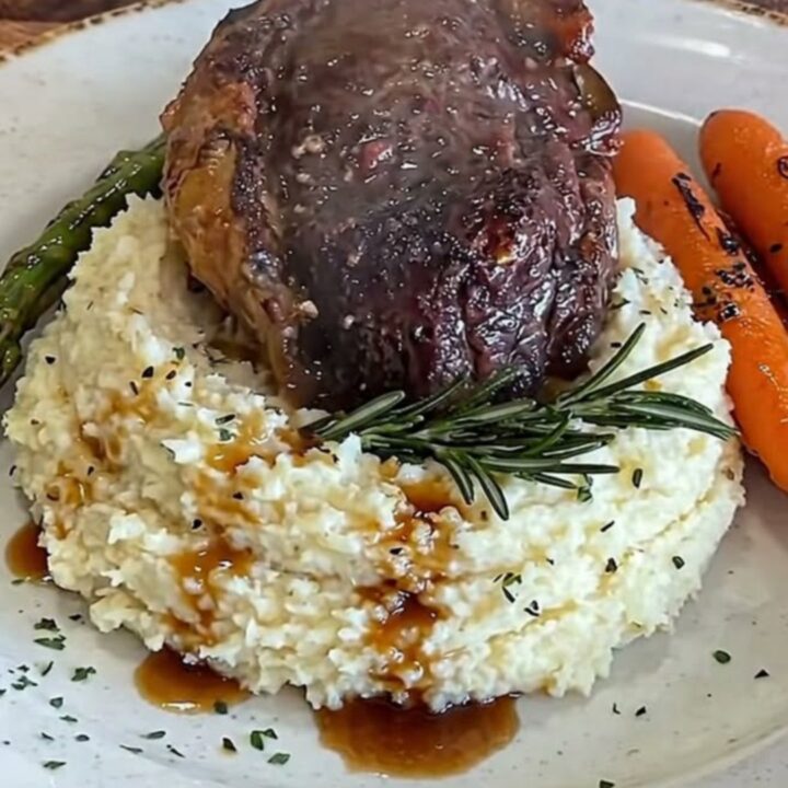 A thick, juicy pan-seared filet mignon steak served over a bed of creamy mashed cauliflower with roasted carrots